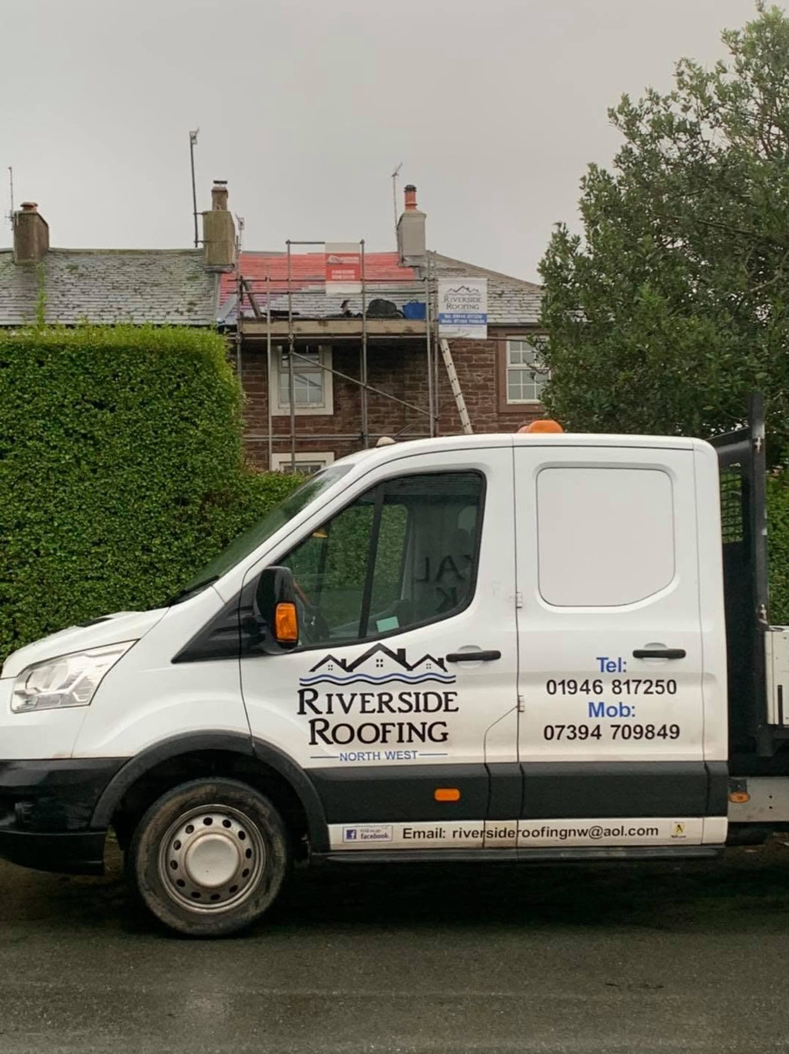 A red sandstone terrace being re-roofed behind scaffolding, with the Riverside Roofing tipper van in front.